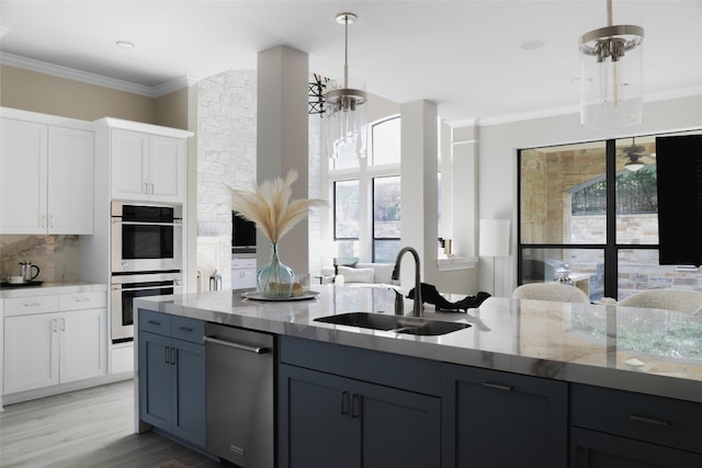 kitchen featuring light stone counters, sink, pendant lighting, white cabinets, and light hardwood / wood-style floors