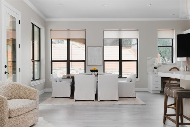 dining space with a healthy amount of sunlight, light hardwood / wood-style floors, and crown molding