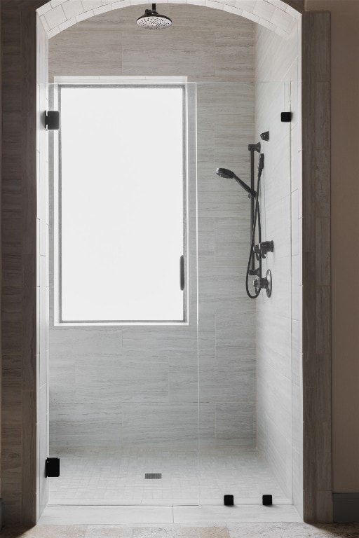 bathroom featuring a shower with door and a healthy amount of sunlight