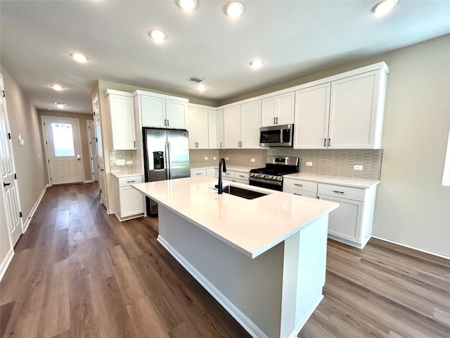 kitchen with hardwood / wood-style floors, appliances with stainless steel finishes, a kitchen island with sink, and white cabinetry