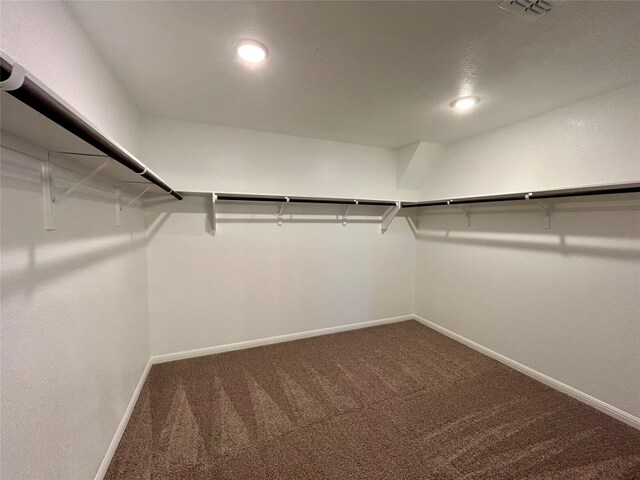 walk in closet featuring dark carpet