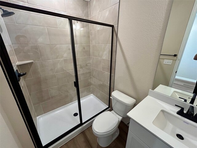 bathroom with vanity, an enclosed shower, hardwood / wood-style flooring, and toilet