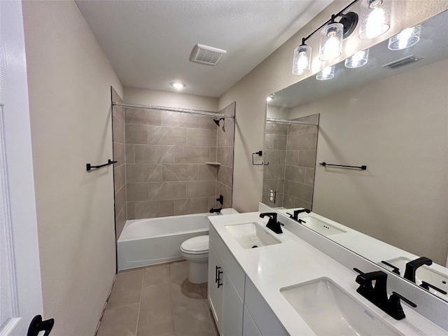 full bathroom featuring a textured ceiling, toilet, tile patterned floors, vanity, and tiled shower / bath combo