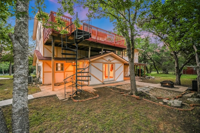 back house at dusk with a wooden deck and central air condition unit