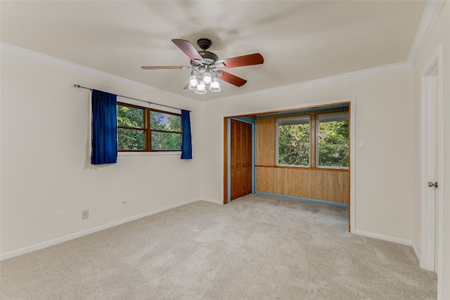 carpeted empty room with a wealth of natural light, ceiling fan, and crown molding