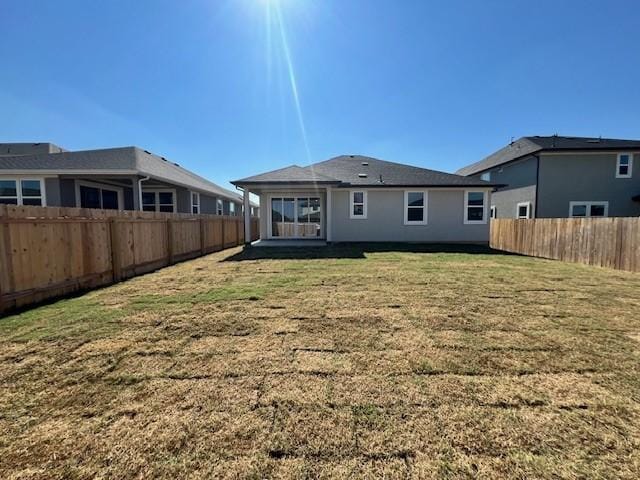 back of house with a fenced backyard and a lawn