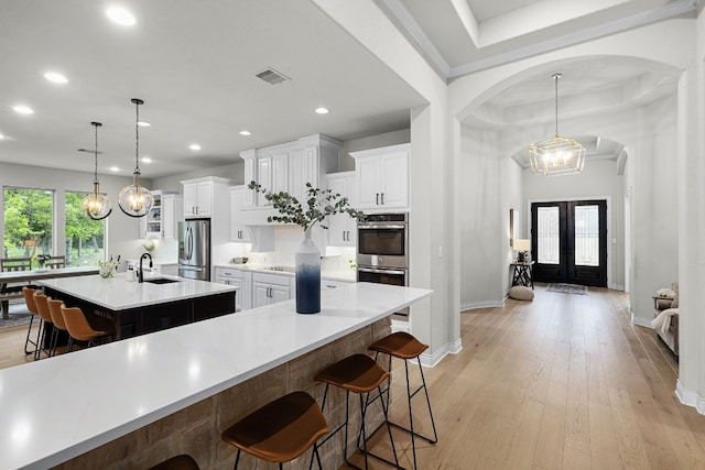 kitchen with a spacious island, white cabinets, appliances with stainless steel finishes, and hanging light fixtures