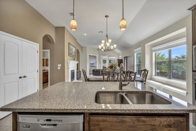 kitchen with light stone countertops, dishwasher, sink, and decorative light fixtures