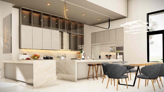 kitchen featuring tasteful backsplash, a breakfast bar, kitchen peninsula, and a high ceiling