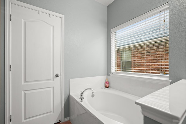 bathroom featuring plenty of natural light and a tub