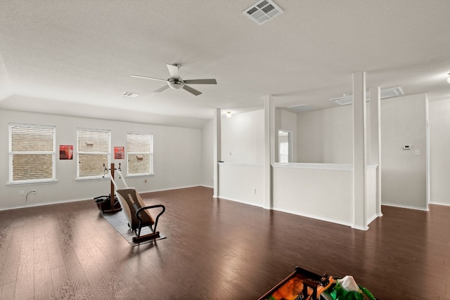 exercise room with ceiling fan, dark wood-type flooring, and a textured ceiling