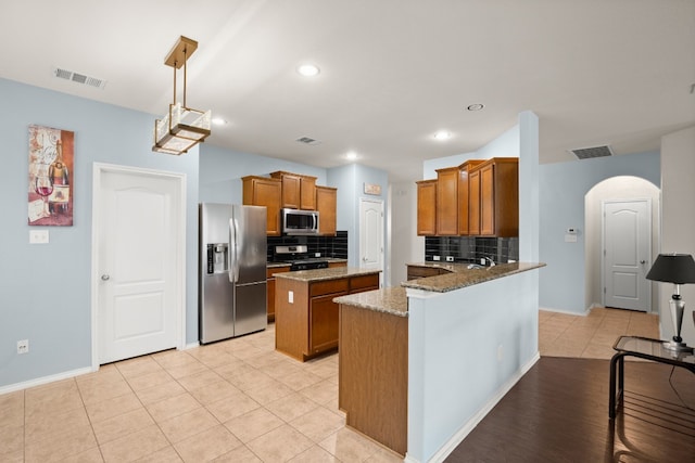 kitchen featuring appliances with stainless steel finishes, tasteful backsplash, hanging light fixtures, kitchen peninsula, and light stone countertops