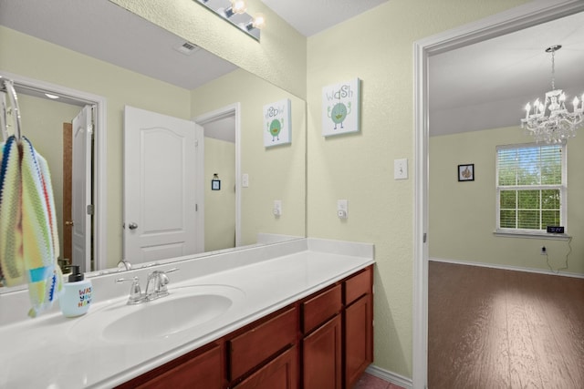 bathroom with vanity, hardwood / wood-style flooring, and an inviting chandelier