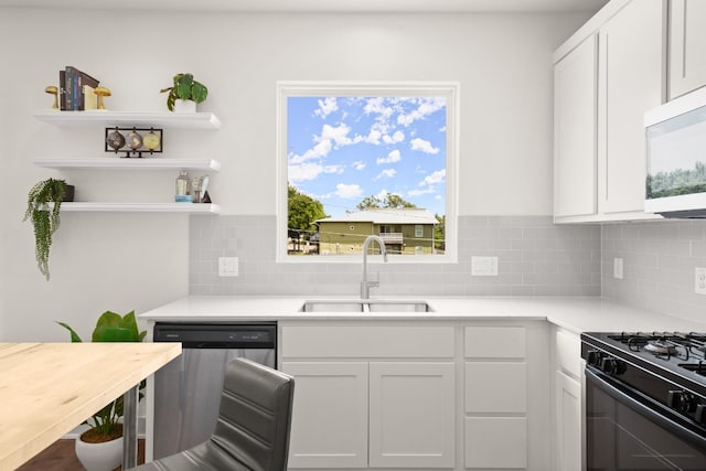 kitchen featuring stainless steel dishwasher, white cabinets, black gas range, sink, and backsplash