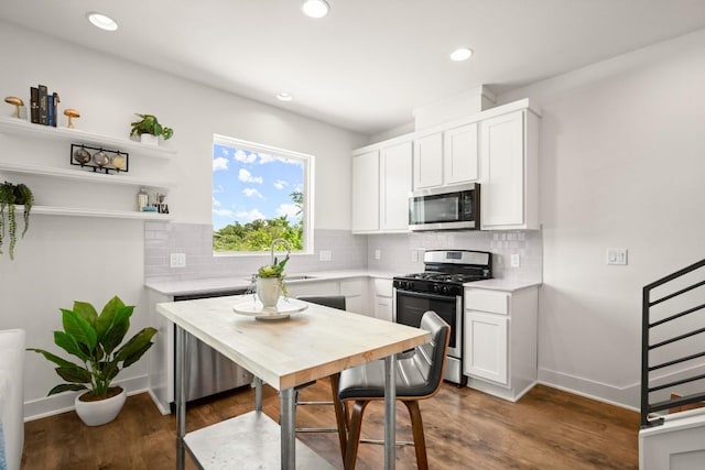 kitchen with sink, backsplash, stainless steel appliances, white cabinets, and dark hardwood / wood-style flooring