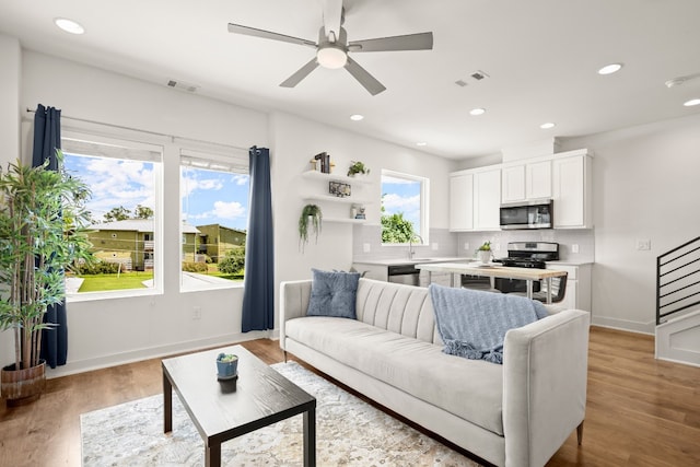 living room with sink, light wood-type flooring, and ceiling fan