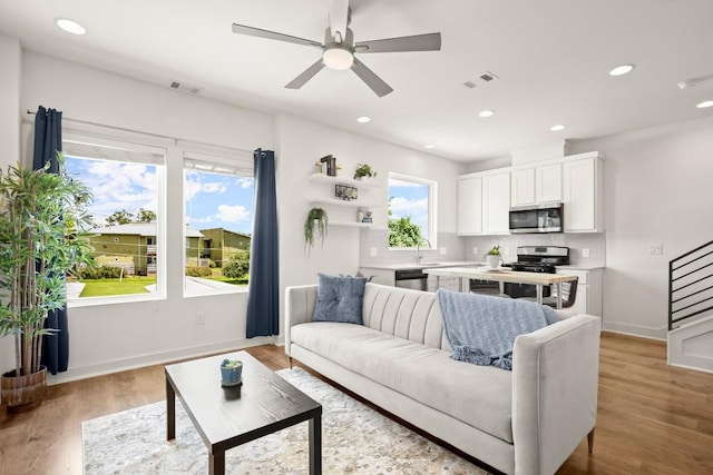 living room featuring ceiling fan, sink, and light hardwood / wood-style floors