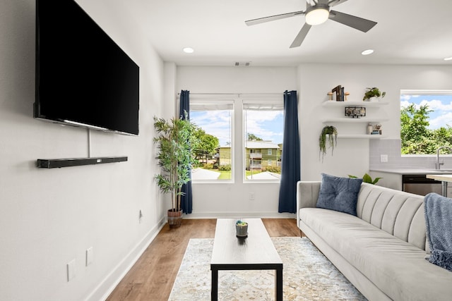 living room with light hardwood / wood-style flooring and ceiling fan