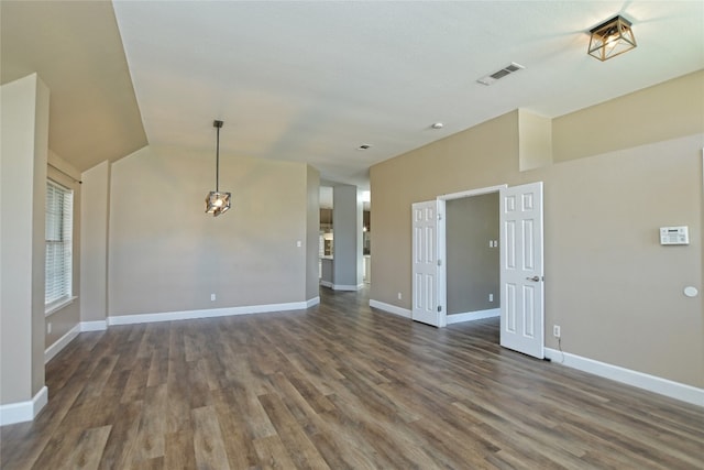 spare room featuring dark wood-type flooring and vaulted ceiling