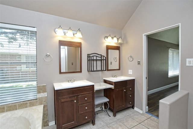 bathroom featuring vanity, tile patterned flooring, a bath, and vaulted ceiling