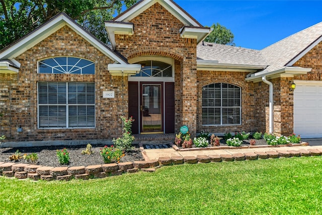 view of exterior entry with a garage and a lawn