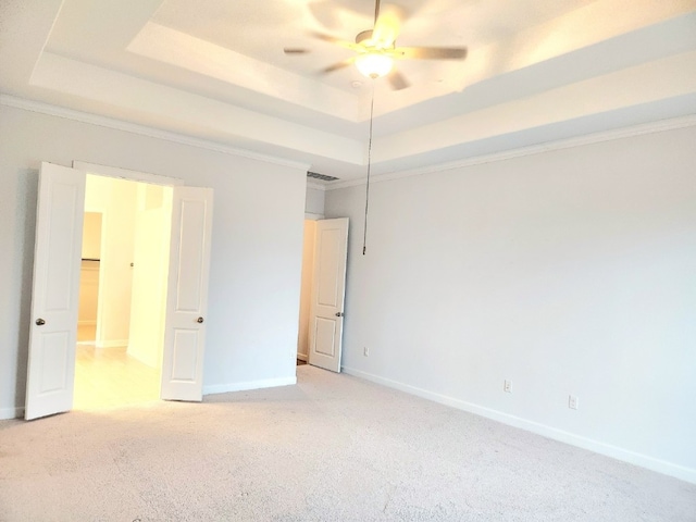 carpeted spare room with ceiling fan, a tray ceiling, and crown molding