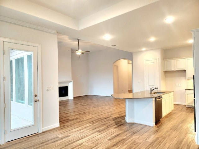 kitchen with ceiling fan, dishwasher, an island with sink, white cabinetry, and light wood-type flooring