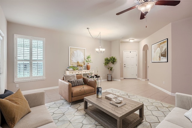 tiled living room with ceiling fan with notable chandelier