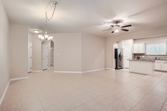 unfurnished living room with ceiling fan with notable chandelier and light tile floors