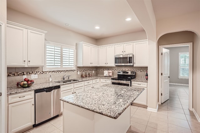 kitchen featuring light tile flooring, appliances with stainless steel finishes, sink, a kitchen island, and tasteful backsplash