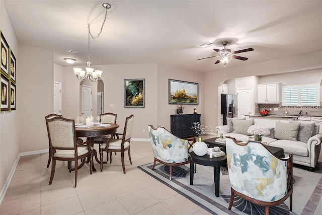 living room featuring light tile flooring and ceiling fan with notable chandelier