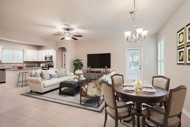 tiled dining area featuring ceiling fan with notable chandelier