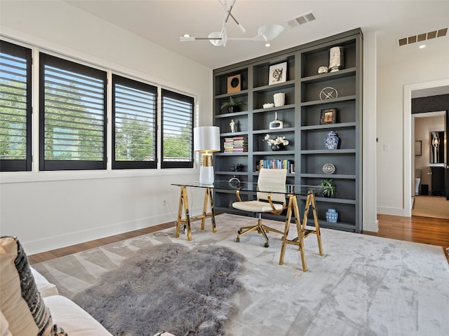 office space featuring hardwood / wood-style floors, an inviting chandelier, and built in shelves