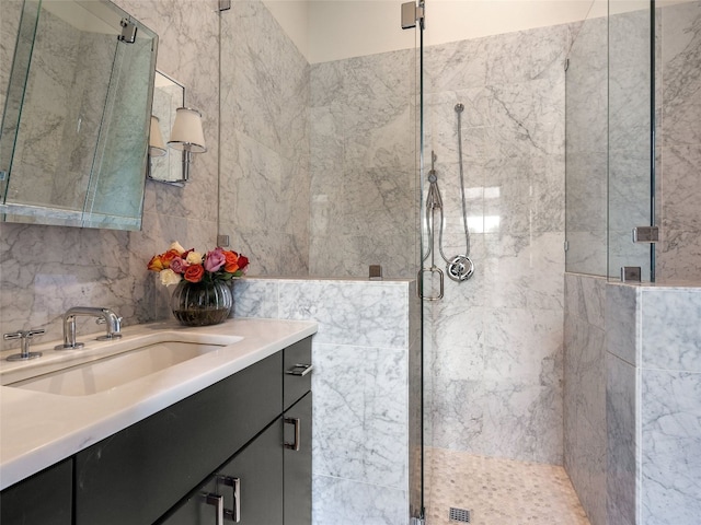 bathroom with tiled shower, vanity, and tile walls