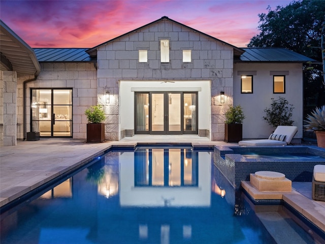 pool at dusk featuring a patio and french doors