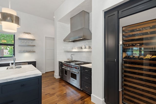 kitchen featuring beverage cooler, wall chimney range hood, backsplash, range with two ovens, and dark hardwood / wood-style flooring