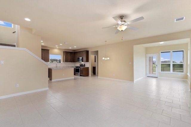 unfurnished living room featuring sink, light tile patterned floors, and ceiling fan with notable chandelier