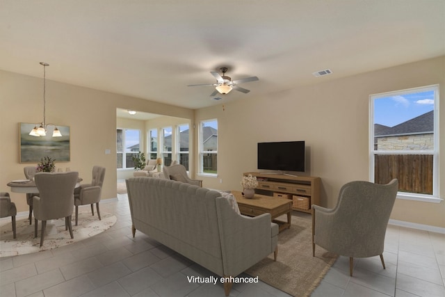 tiled living room with ceiling fan with notable chandelier