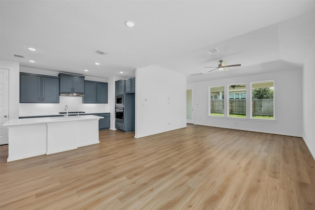 kitchen featuring open floor plan, light countertops, a center island with sink, and visible vents