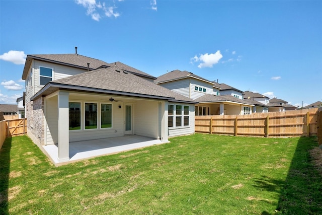 back of property featuring a fenced backyard, ceiling fan, roof with shingles, a yard, and a patio area