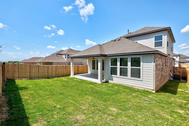 back of house featuring a patio, a fenced backyard, brick siding, a lawn, and roof with shingles