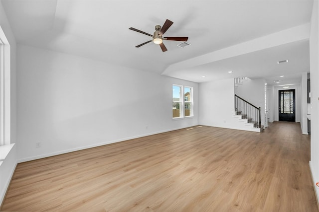 empty room with a ceiling fan, visible vents, stairs, baseboards, and light wood-type flooring