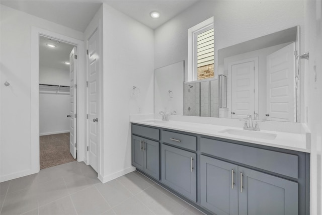 full bath featuring double vanity, a stall shower, a walk in closet, and a sink