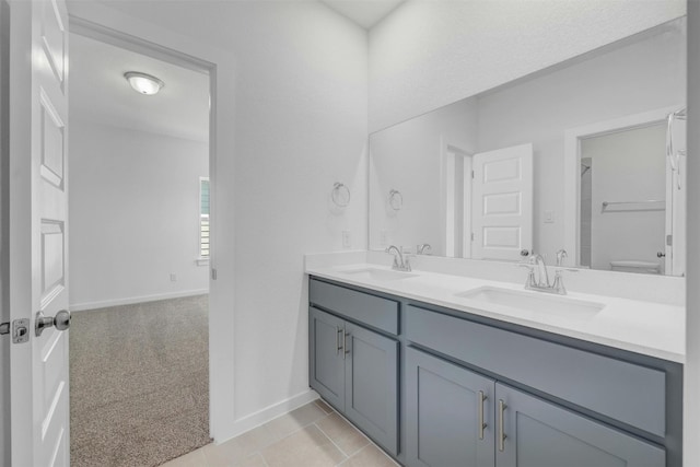 full bathroom featuring double vanity, a sink, toilet, and baseboards