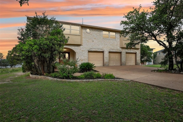 view of front of home featuring driveway, an attached garage, stucco siding, stone siding, and a lawn