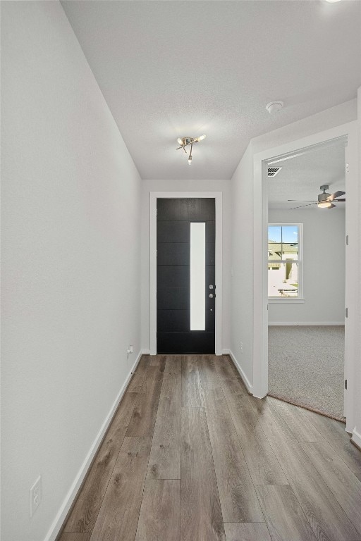 carpeted foyer entrance featuring ceiling fan and a textured ceiling