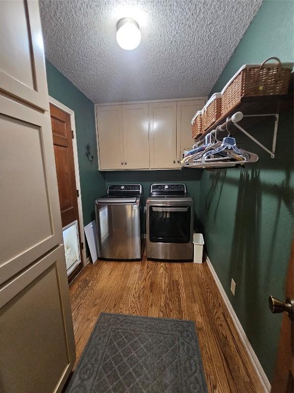 laundry room with hardwood / wood-style floors, cabinets, independent washer and dryer, and a textured ceiling