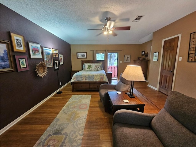 bedroom with ceiling fan, wood-type flooring, and a textured ceiling