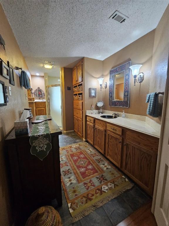 bathroom with hardwood / wood-style floors, vanity, a textured ceiling, and walk in shower