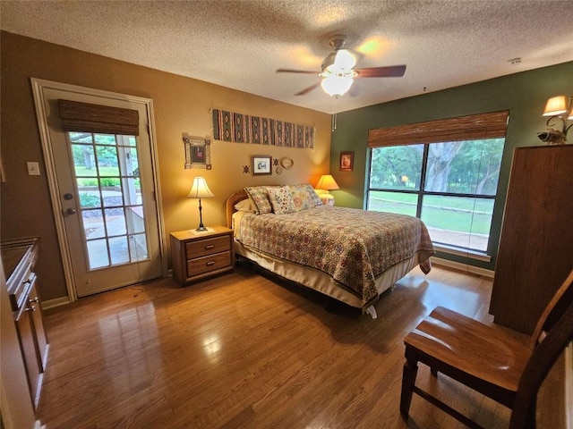 bedroom featuring multiple windows, hardwood / wood-style floors, access to outside, and ceiling fan